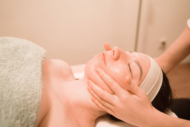 Hermosa joven recibiendo un tratamiento de masaje facial en el salón de belleza
 - Foto, Imagen