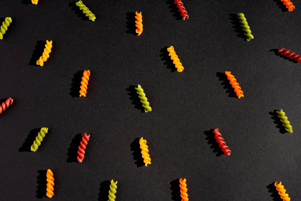 Tricolor-Nudeln auf schwarzem Hintergrund. Archivbild von Pasta. - Foto, Bild