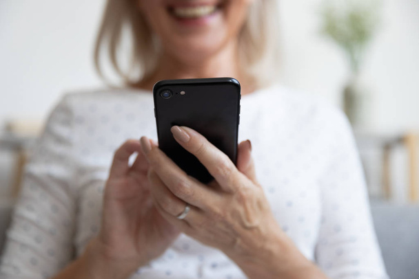 Elderly woman holding smartphone smiling enjoy online activity closeup view - Foto, immagini