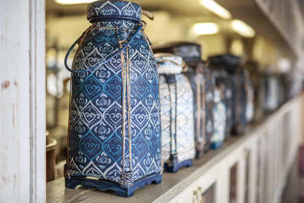 Vase im orientalischen Stil mit aufwändigen Ornamenten steht auf einem hellen hölzernen Vintage-Regal, in einer Reihe vieler Vasen, verschwommener Hintergrund - Foto, Bild