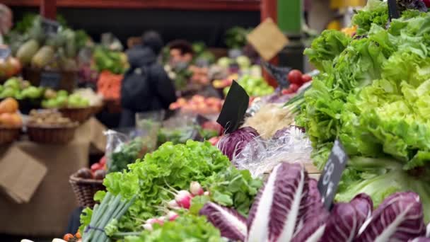 Ludzie przeglądający stoisko owocowo-warzywne w Borough Market w Londynie. Klienci nieostrzy w tle. - Materiał filmowy, wideo