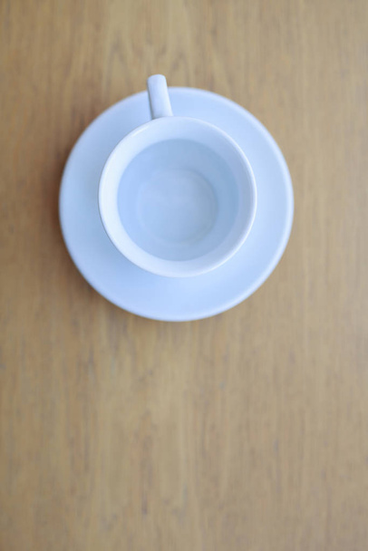 egy fából készült asztal áll egy tiszta fehér kerámia csésze és csészealj - Fotó, kép