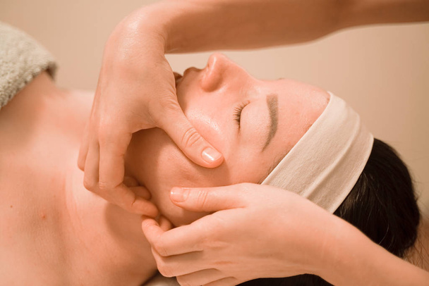 Hermosa joven recibiendo un tratamiento de masaje facial en el salón de belleza
 - Foto, imagen