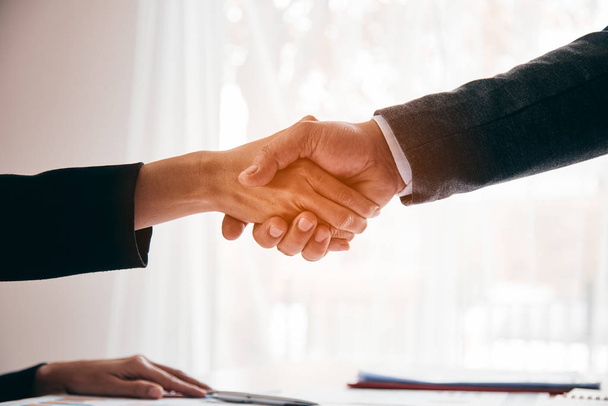 Уверенные деловые мужчины и женщины пожимают друг другу руки во время встречи в офисе, преемственности с торговлей или приветствия партнерской концепции
. - Фото, изображение