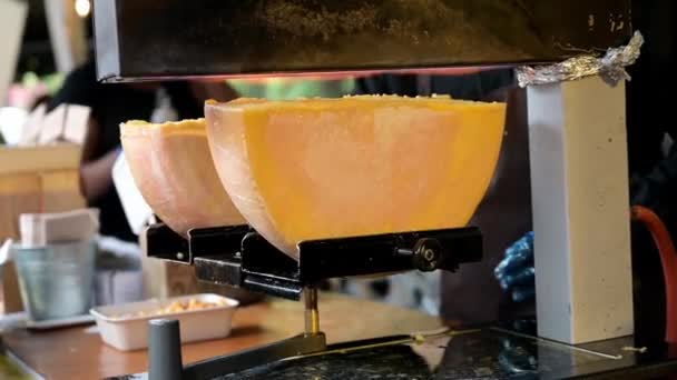 Tradiční sýrová Raclette na stánku s pouličními potravinami v londýnském Borough Market. Pohled na polokola roztaveného sýra pod zářícími plameny nad nimi. - Záběry, video