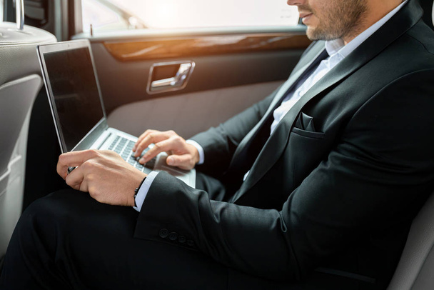 cropped businessman using laptop in car - Photo, image