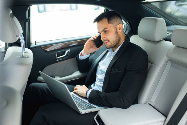 mladý podnikatel v elegantním obleku na zadním sedadle luxusního auta - Fotografie, Obrázek