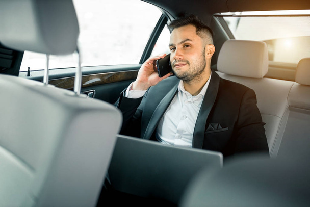 young businessman in elegant suit on backseat of luxurious car - Foto, afbeelding