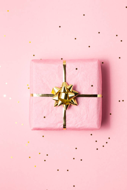 Pink and golden wrapped gift on pink background - Фото, зображення