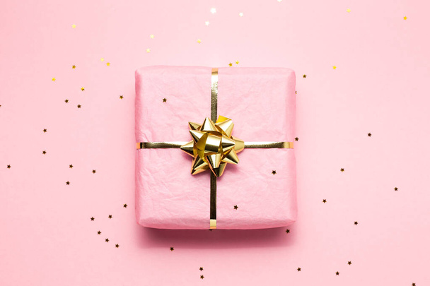 Pink and golden wrapped gift on pink background - Fotografie, Obrázek