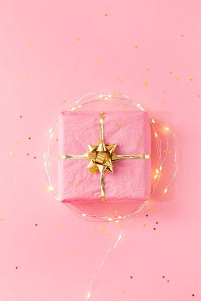 Pink gift with golden bow and decorative lights - Фото, изображение