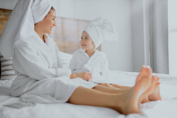 lovely family, mother and daughter lying on bed together after shower - 写真・画像