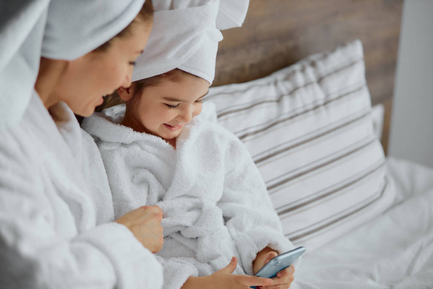 smiling happy girl in bathrobe and towel use smartphone - 写真・画像