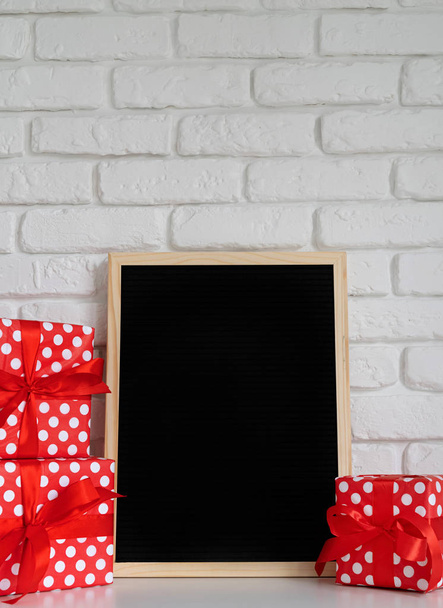 μαύρη μακέτα μέχρι τσόχινο πίνακα επιστολών με κόκκινα κουτιά δώρων σε λευκό φόντο τούβλο - Φωτογραφία, εικόνα
