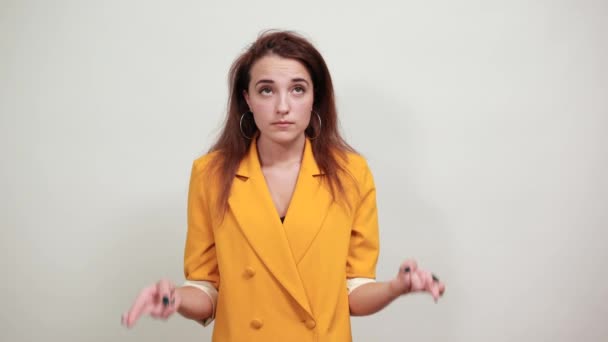 Attractive woman in yellow jacket keeping finger crossed, looking confused - Záběry, video
