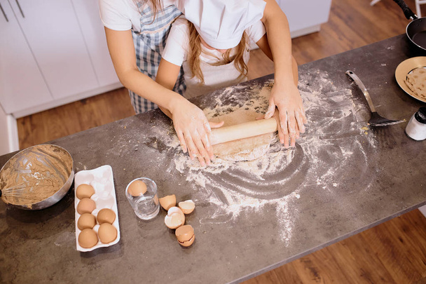 caucasian woman teaching daughter how to roll the dough - 写真・画像