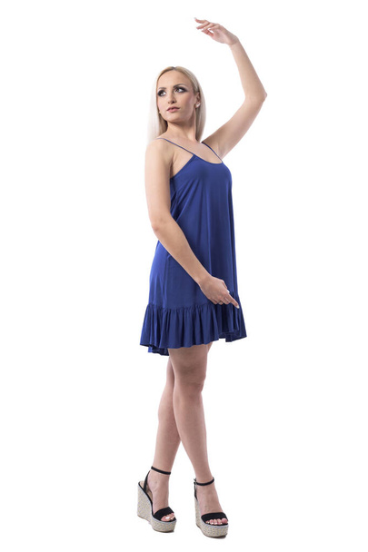 Ballerina stance or posture. Elegant feminine blond girl posing with hand raised up. Full body isolated on white background.  - Photo, Image