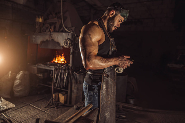 side view on blacksmith having rest at work place - Foto, imagen