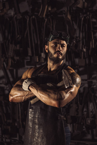 Retrato de confiante forte jovem metalúrgico em avental preto
 - Foto, Imagem
