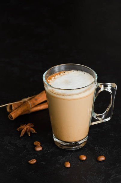 Glass of coffee with milk on black background. Hot latte or cappuccino in transparent mug. Morning beverage. A good start to the day concept. Close-up. Copy space - 写真・画像