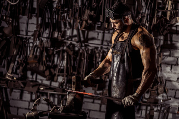 young blacksmith forging molten metal - Fotó, kép