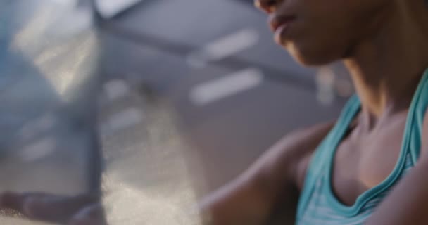 Low angle close up of an athletic mixed race woman wearing sports clothes cross training at a gym, wrapping her hands in preparation for boxing training, slow motion - Video