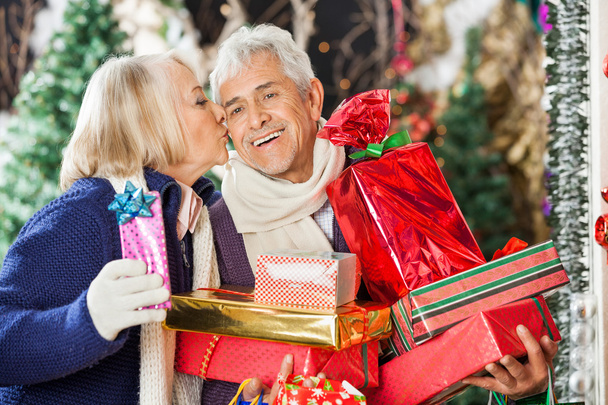 Жінка цілує чоловіка тримає різдвяні подарунки
 - Фото, зображення