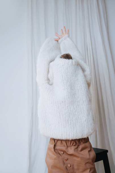 Funny little girl trying to break her head and hands free from inside of sweater - Fotoğraf, Görsel