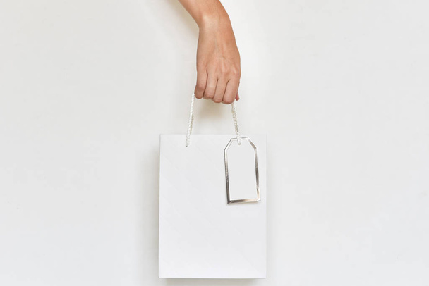 bolsa de compras de papel de mano de mujer sobre un fondo blanco, cierre
  - Foto, imagen
