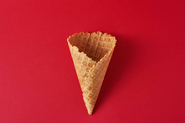 Empty ice cream cone on the red background, top view flat lay. Minimalism style creativity concept - Fotoğraf, Görsel