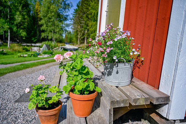 flores en las escaleras frente a una cabaña de madera roja
 - Foto, Imagen