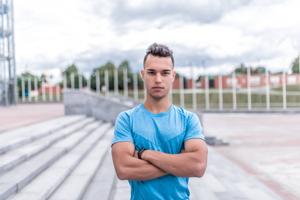 Portrait of handsome, athletic man posing, coach controls exercises, training in summer day in city, active lifestyle, modern fitness workout. Free space for motivation text. - Valokuva, kuva