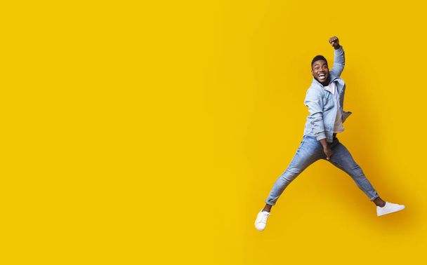 Портрет прыгающего черного парня на фоне жёлтой студии
 - Фото, изображение