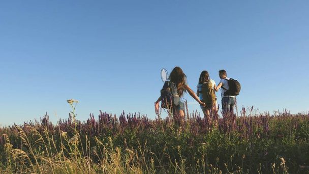 teamwork of tourists. travelers go with backpacks through the meadow. Family of tourists with children in the countryside. travelers admire the beautiful scenery and nature. movement to victory. - Photo, Image