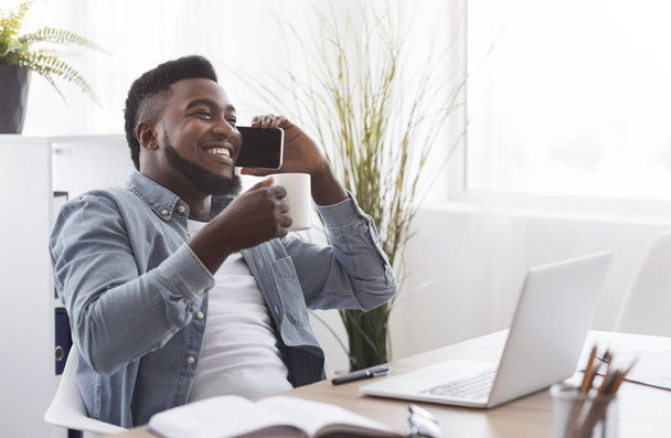 schwarzer Geschäftsmann macht Kaffeepause und telefoniert im Büro - Foto, Bild