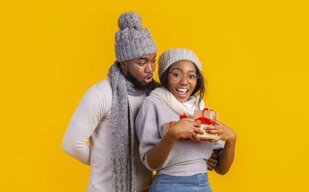 Felice afro inverno ragazza in possesso di regali di Natale, fidanzato rimanere dietro
 - Foto, immagini