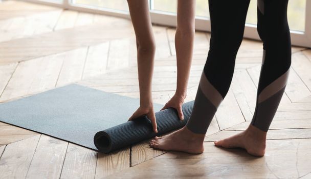 Frau rollt Yogamatte, beendet ihre Praxis - Foto, Bild