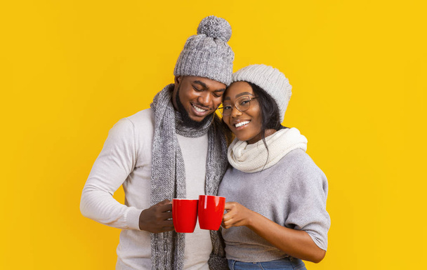Zimní veselý chlap a dívka pití kávy přes žluté pozadí - Fotografie, Obrázek