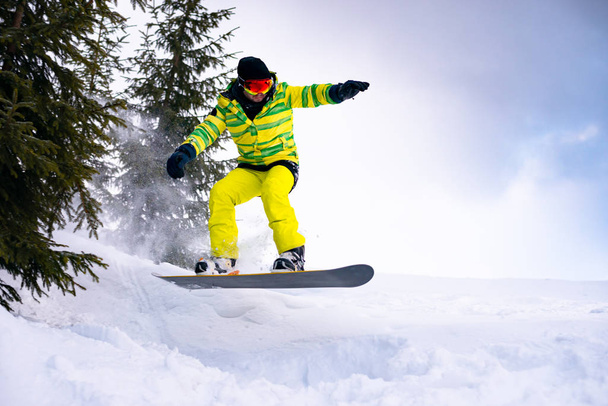 Snowboarder Riding Snowboard in the Forest at Cloudy Day. Snowboarding and Winter Sports - Фото, изображение