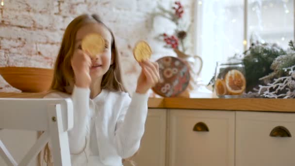 Mosolygó szőke lány eltakarja a szemét szárított citrusszeletekkel otthon tetőtéri stílussal és karácsonyi dekorációval, boldog gyermekkori koncepció - Felvétel, videó