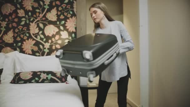 Pretty businesswoman putting suitcase on bed in hotel. Young girl open luggage - Metraje, vídeo