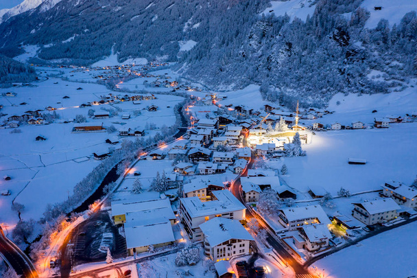 Paysage urbain du matin d'hiver dans la ville autrichienne de Neustift. Vue aérienne du centre-ville et de l'église. Éclairage matinal des maisons et des feux de circulation. Tyrol, vallée de Stubai
 - Photo, image