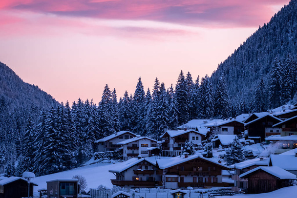 typisch Oostenrijks dorp op een winterochtend bij zonsopgang. Snowy winterwoudbomen en Tiroolse huizen - Foto, afbeelding
