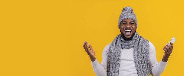 Emocionální afro chlap křičí a zvedá ruce, drží telefon - Fotografie, Obrázek