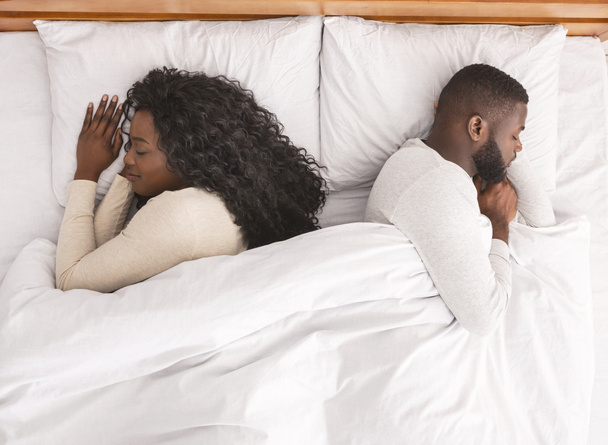 Jeune couple afro sieste dos à dos dans un lit confortable
 - Photo, image