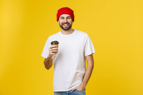Hombre en color amarillo vibrante aislado tomando un café en una taza de papel para llevar y sonriendo porque comenzará bien el día
. - Foto, imagen