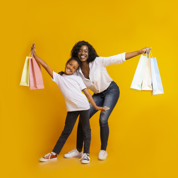 Porträt einer fröhlichen schwarzen Mutter und Tochter mit bunten Einkaufstüten - Foto, Bild