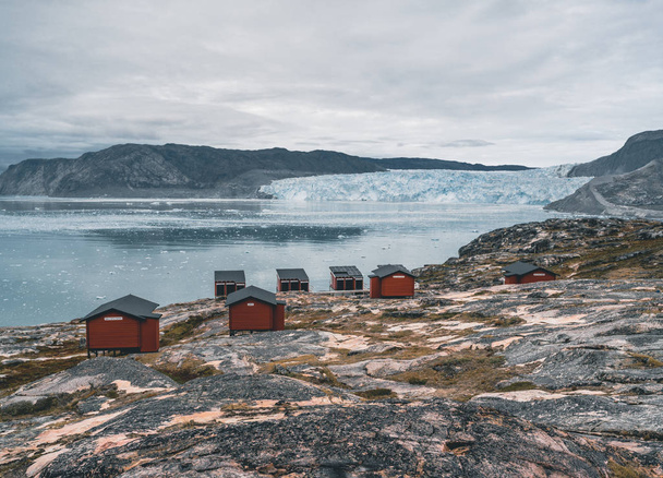 Panoramic image of Camp Eqi at Eqip Sermia Glacier in Greenland. nature landscape with lodge cabins. Midnight sun and pink sky. Tourist destination Eqi glacier in West Greenland AKA Ilulissat and - Fotografie, Obrázek