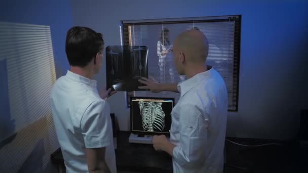 En la sala de control, el médico y el radiólogo discuten el diagnóstico mientras observan el procedimiento, en segundo plano, el paciente se somete a una resonancia magnética o a un procedimiento de exploración por TC
. - Metraje, vídeo