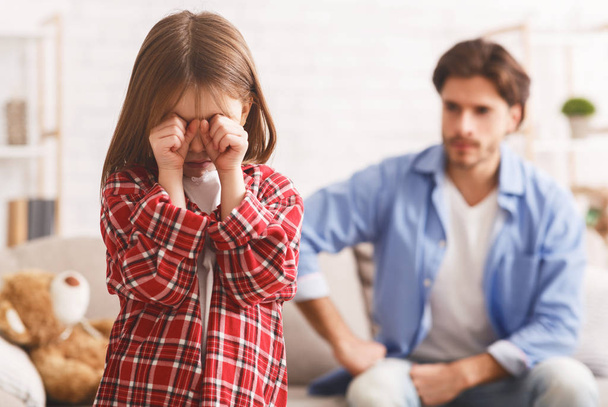 Petite fille pleurant après s'être disputée avec papa, père en colère derrière
 - Photo, image